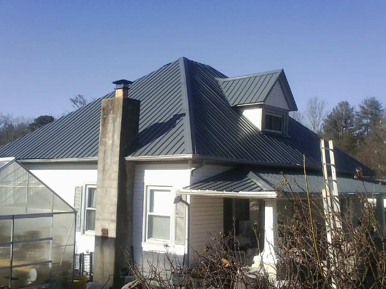 Dark blue standing seam metal roof on a white farmhouse with dormer — Slate & Tile Roof Repair by Roofing Brothers in Wamego
