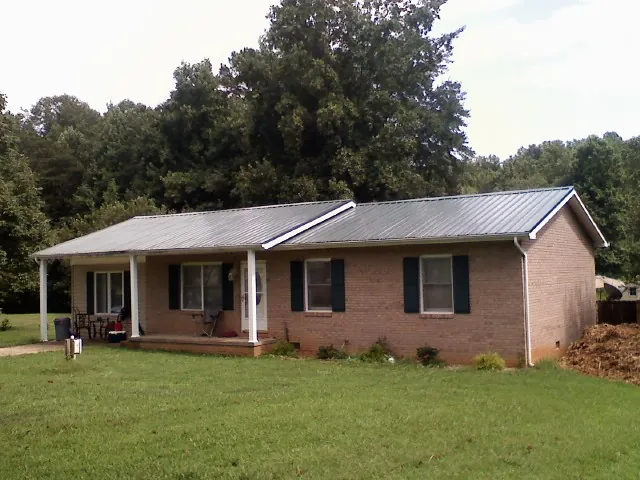 Gray metal roof on a brick ranch house with a side carport in Wamego