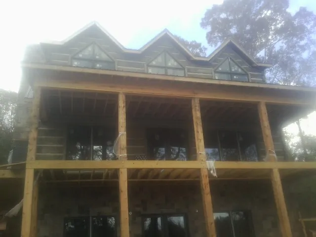 Dormers and porch framing on a large log home under construction — Roof Coating work by our crew in Wamego