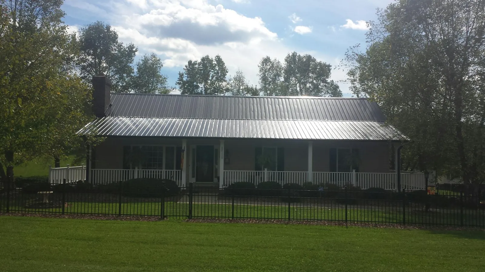 Gray metal roof on a brick ranch with a full width front porch — Gutter Guard Installation work by our crew in Wamego