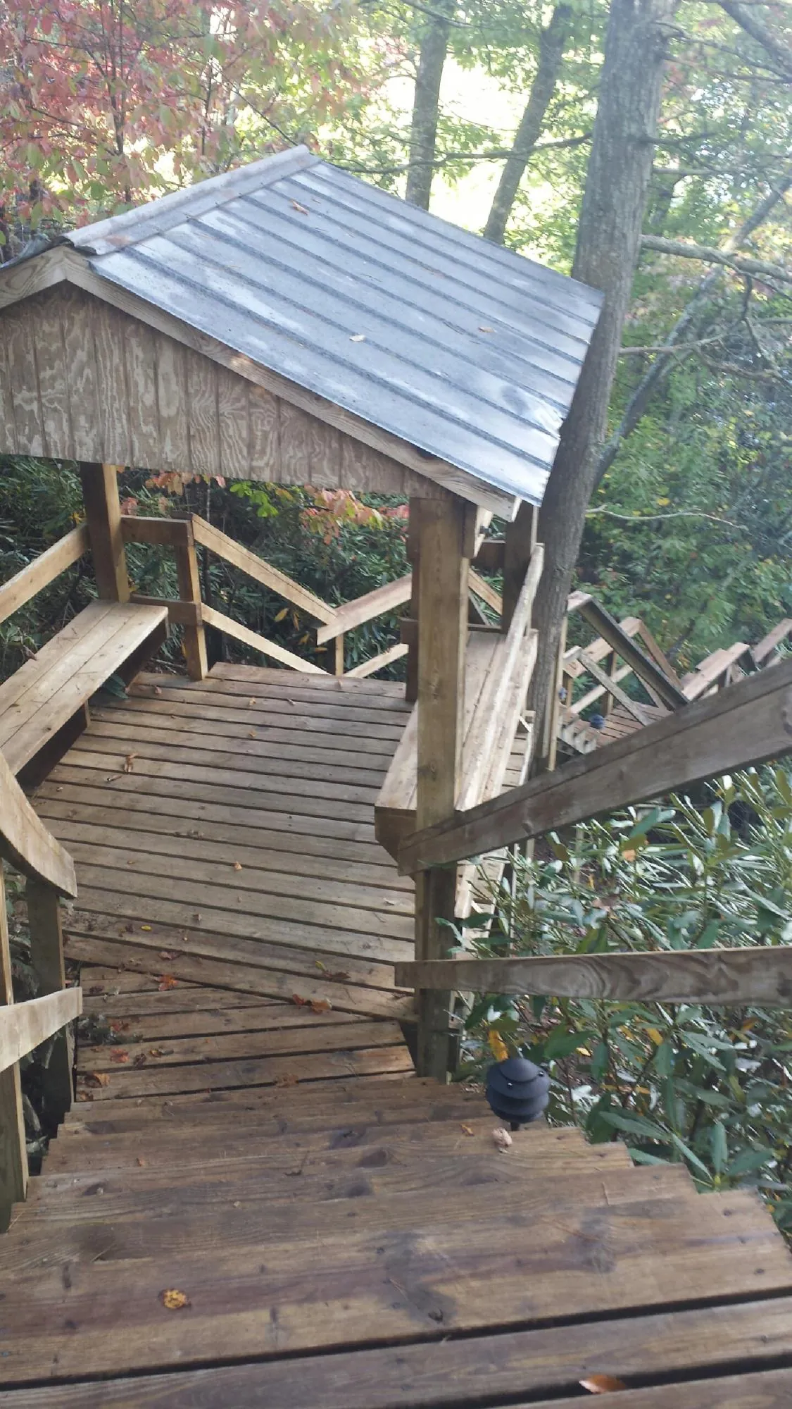 Metal roofed shelter over wooden steps on a wooded walkway — Skylight Repair & Installation work by our crew in Wamego
