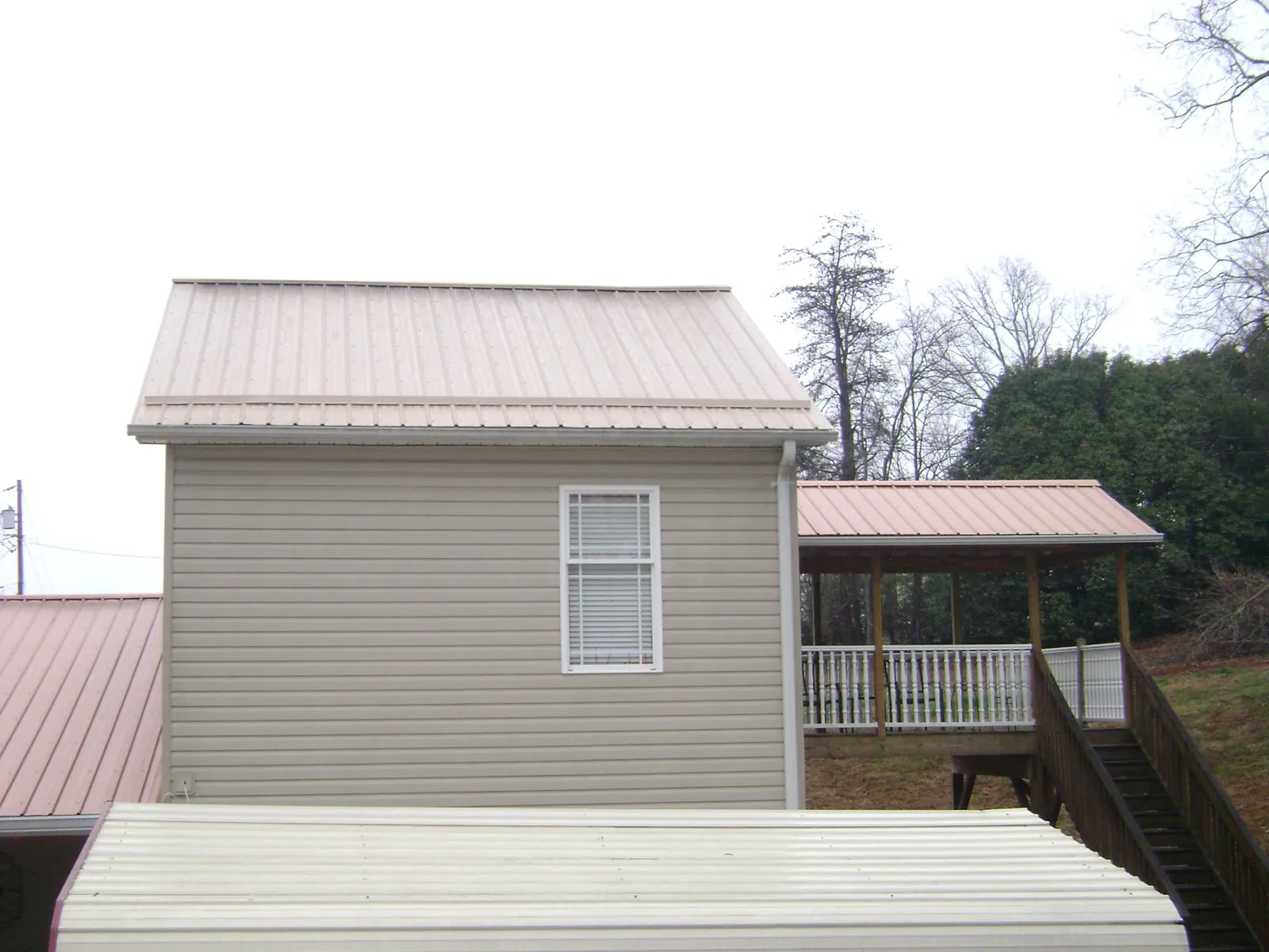 Tan metal roofs on a two story addition and attached porch, from a Roof Replacement job in Wamego