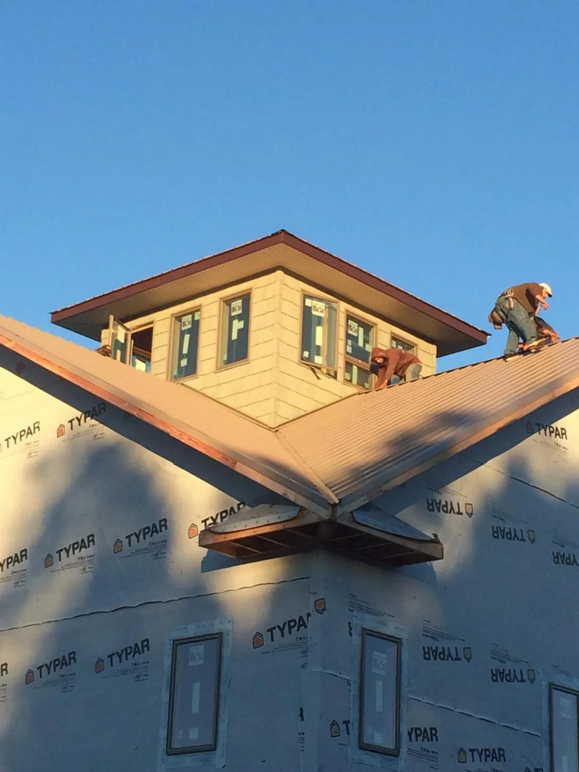 Roofers working around a rooftop cupola on a new metal roof at sunset — Roof Waterproofing in Wamego by Roofing Brothers